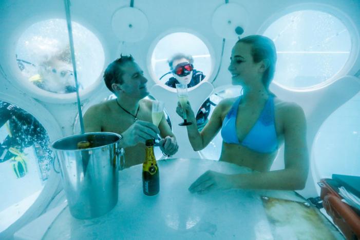 Belgians Florence Lutje Spelberg and Nicolas Mouchart drink champagne while sitting inside “The Pearl”, a spheric dining room placed 5 metres underwater in the NEMO33 diving center in Brussels