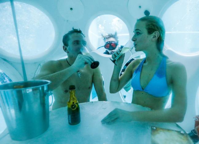 Belgians Florence Lutje Spelberg and Nicolas Mouchart drink champagne while sitting inside “The Pearl”, a spheric dining room placed 5 metres underwater in the NEMO33 diving center in Brussels
