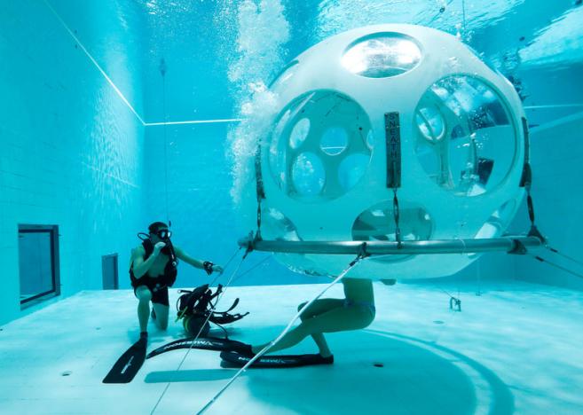 Belgians Florence Lutje Spelberg and Nicolas Mouchart dive into “The Pearl”, a spheric dining room placed 5 metres underwater in the NEMO33 diving center in Brussels